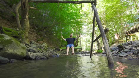 The-young-man-swinging-on-the-swing-in-the-creek.